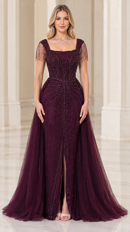 Front view of woman wearing burgundy square neck beaded evening gown with front slit and tulle overskirt