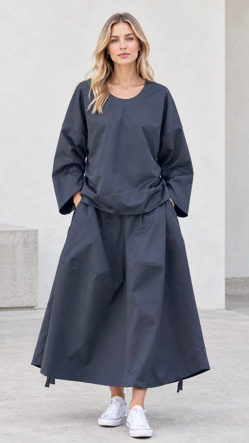 Front view of model wearing charcoal grey two-piece long sleeve top and maxi skirt set