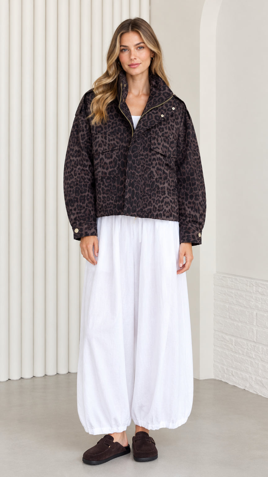 Front view of model wearing dark brown leopard print cropped jacket with wide white trousers