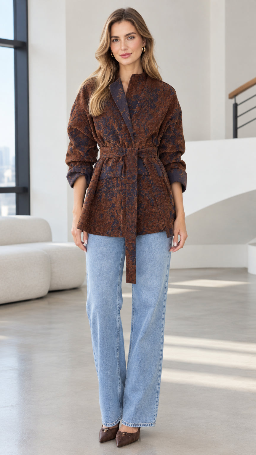 Front view of model wearing rust brown floral jacquard belted wrap jacket with jeans