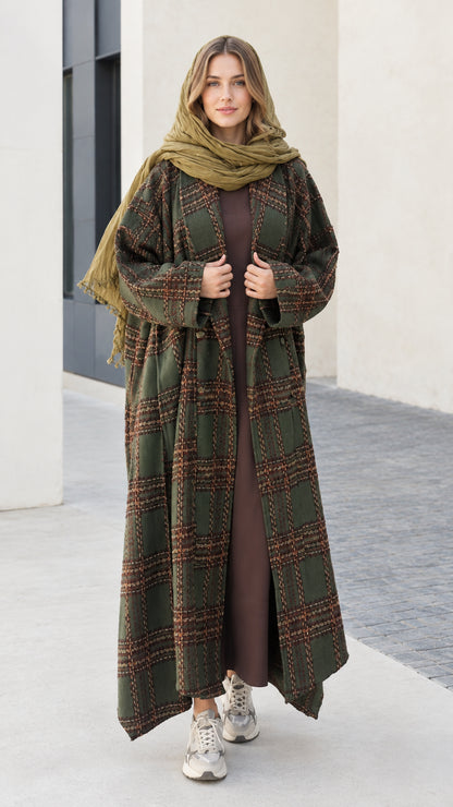 Front view of woman wearing olive green plaid maxi duster coat with matching green scarf