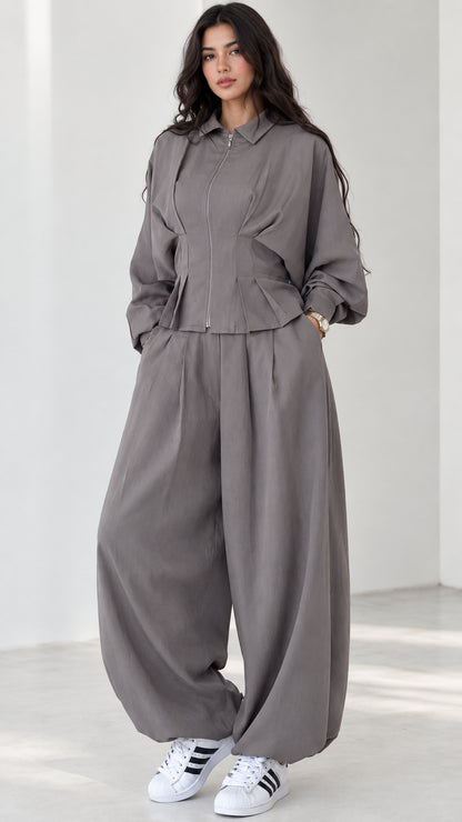 Model wearing grey zip-front top and balloon pants matching two-piece set front view