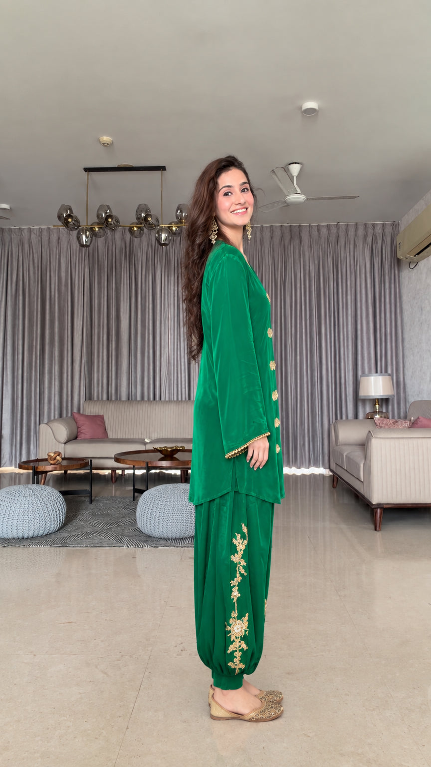 Side profile of emerald green two-piece satin tunic and cuffed salwar pant set