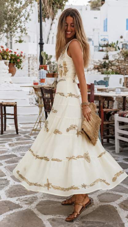 Side view of ivory sleeveless embroidered tiered maxi dress with flowing full skirt