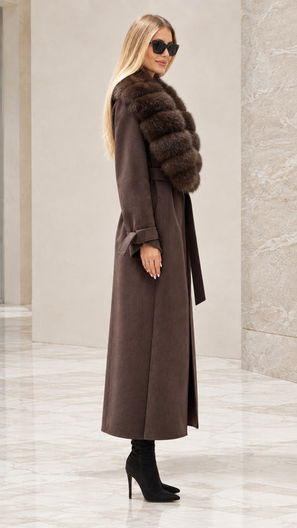 Side profile of woman wearing brown belted maxi coat with faux fur trim