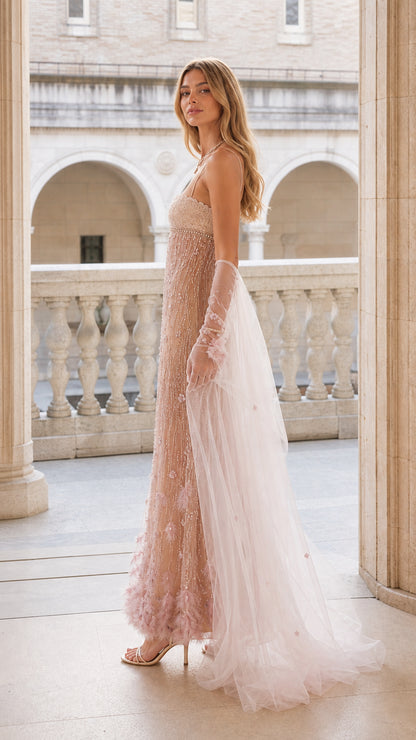 Side profile view of blush pink beaded evening gown with sheer cape