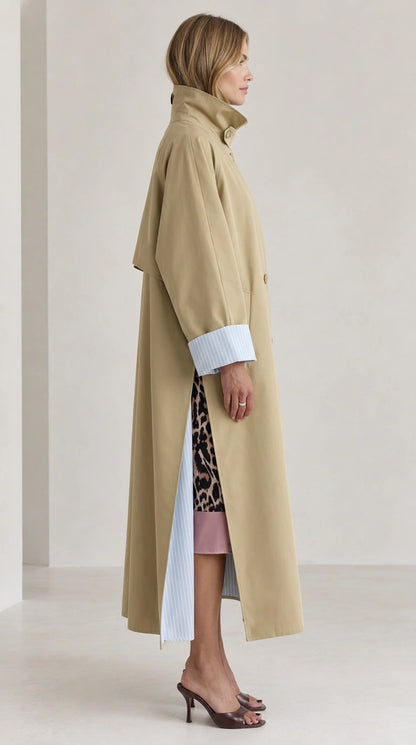 Side profile of woman in khaki maxi trench coat showing high collar and side slit