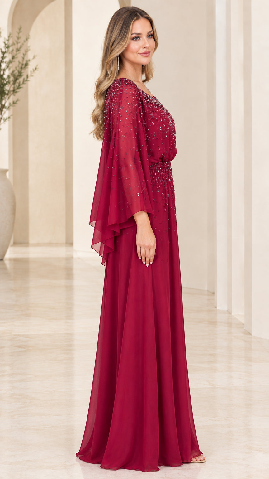 Side view of burgundy floor length formal gown with sheer cape sleeves