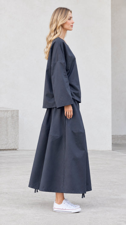 Side view of model wearing charcoal grey matching skirt and top set with white sneakers