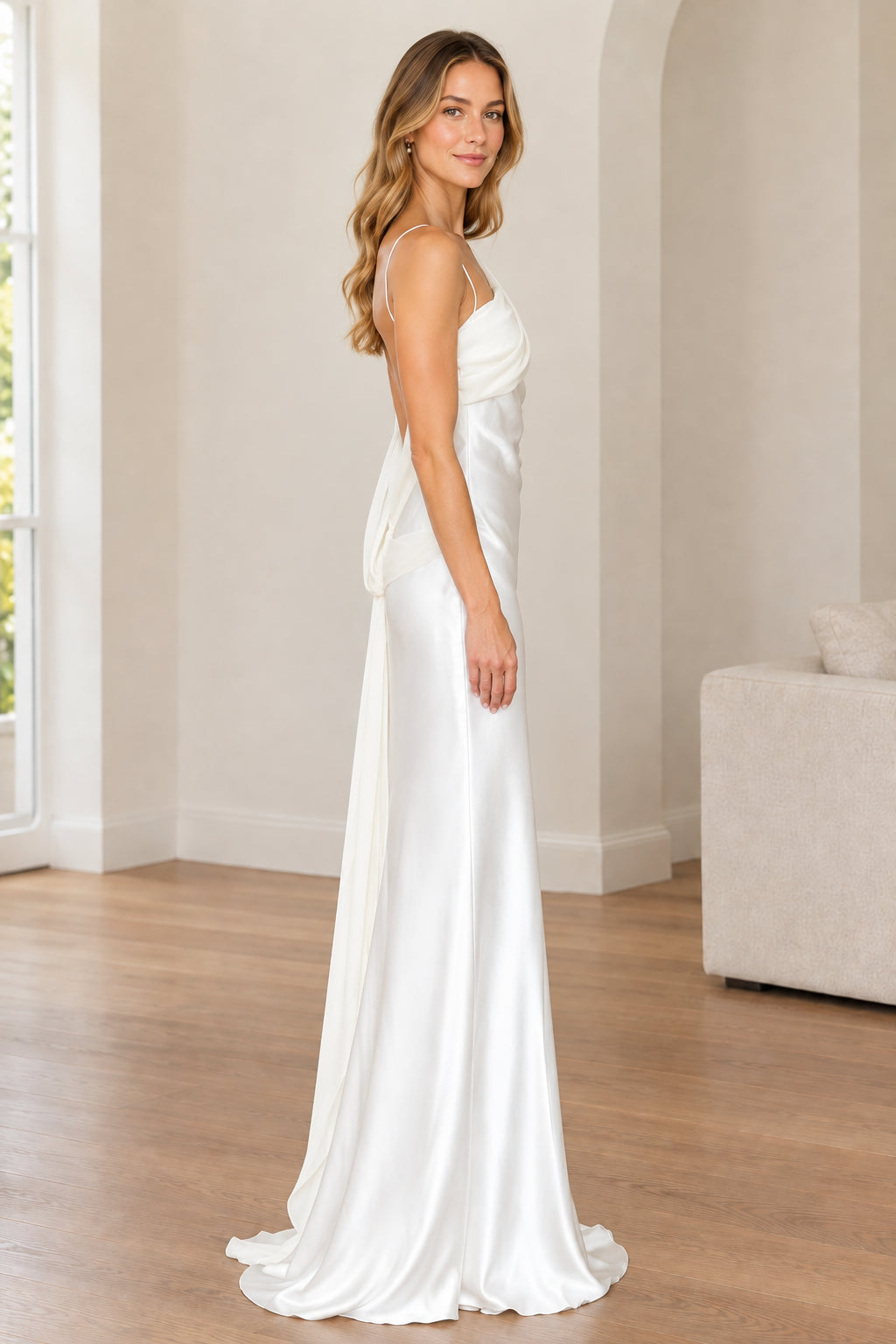 Side angle view of woman modeling white draped one-shoulder evening gown
