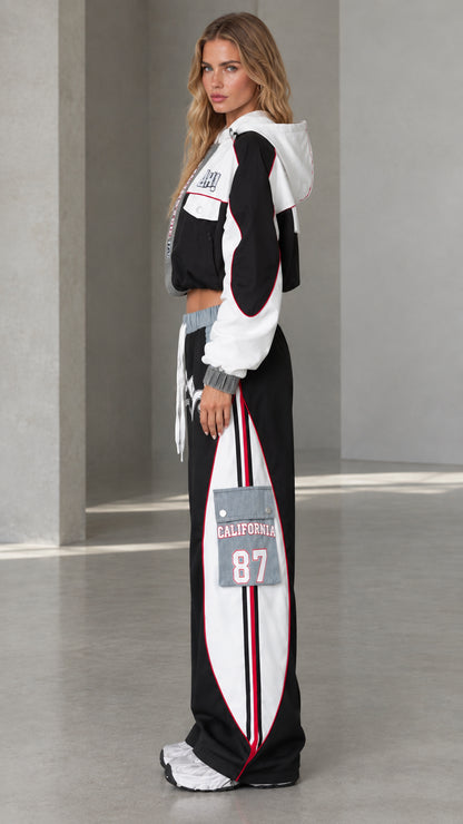 Side profile of model wearing black two-piece streetwear tracksuit set