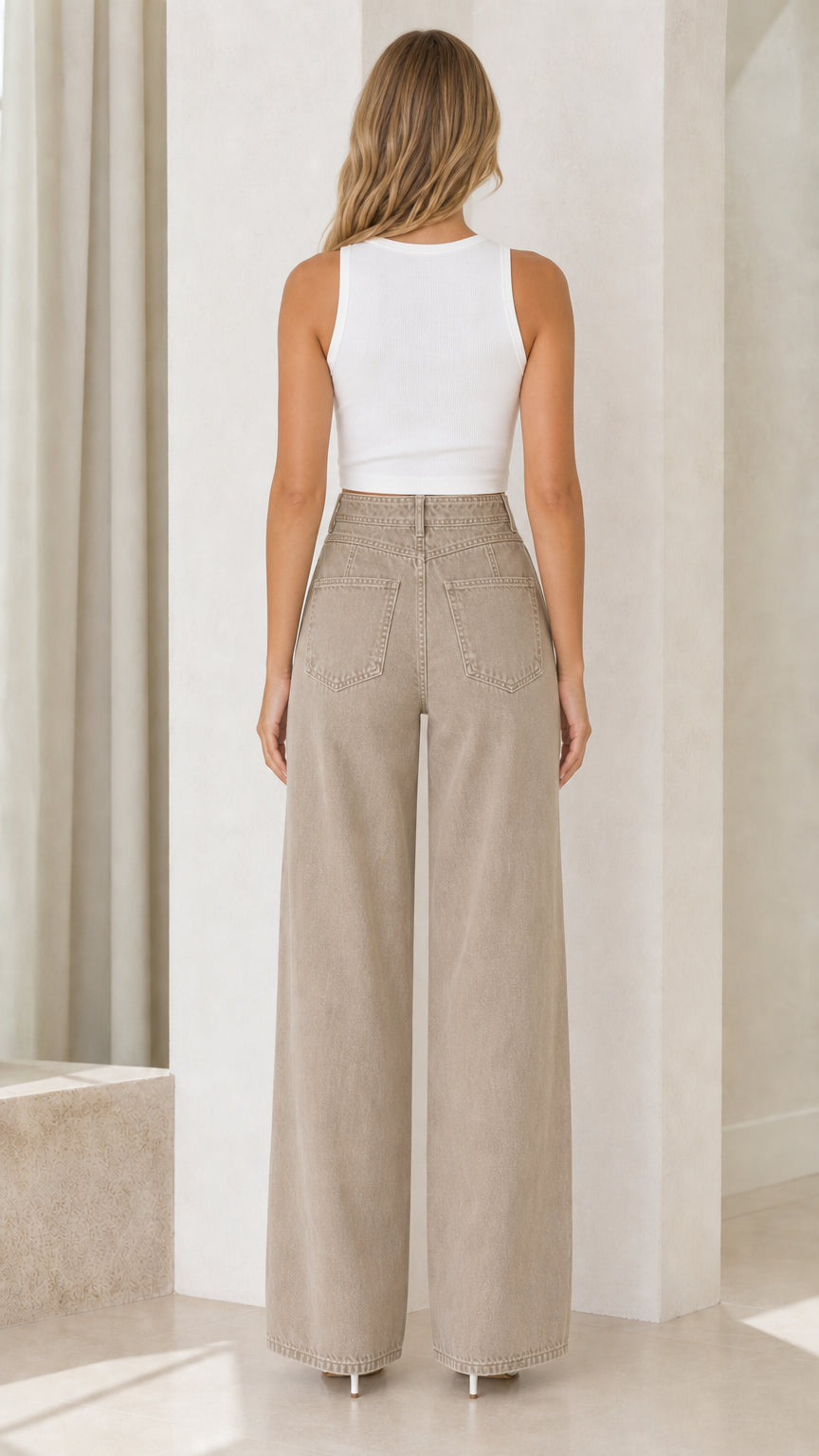 Back view of model wearing taupe high-waisted wide-leg denim trousers