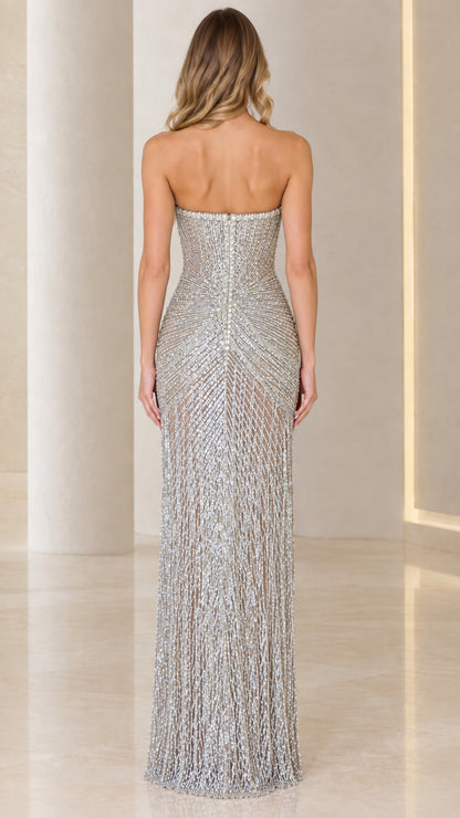 Back view of model wearing fitted silver strapless beaded formal gown