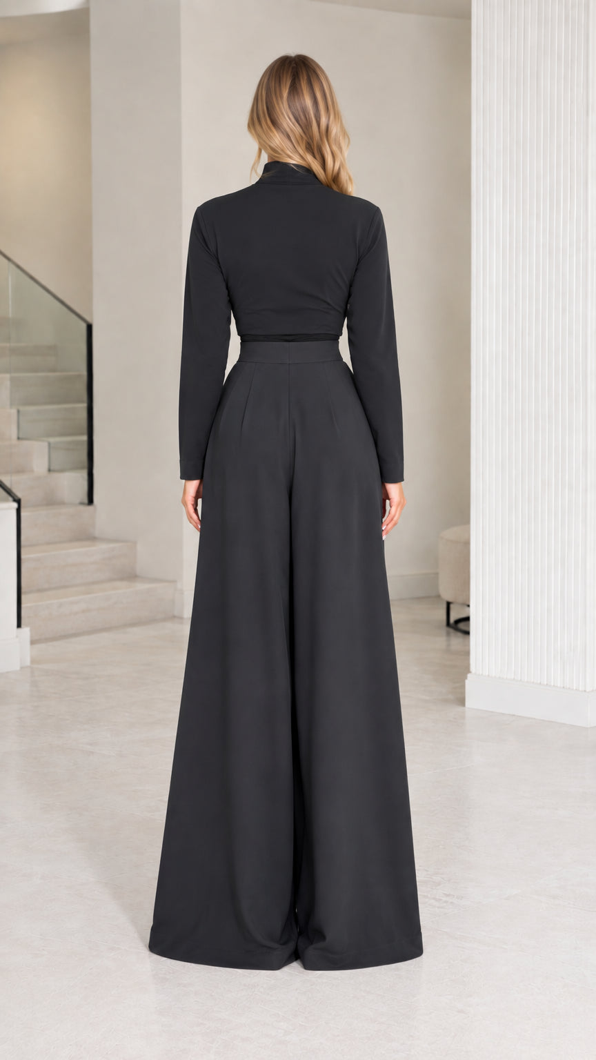 Back view of model wearing tailored black mock neck top and flowy wide-leg pants