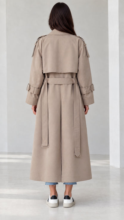 Back view of beige trench coat highlighting storm flap and belted waist design