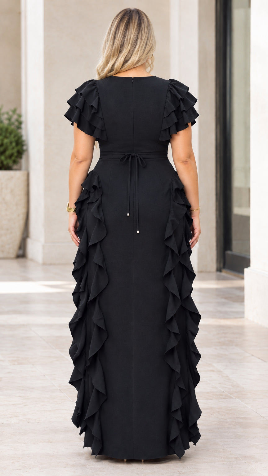 Back view of model wearing black maxi dress showing back tie and zipper