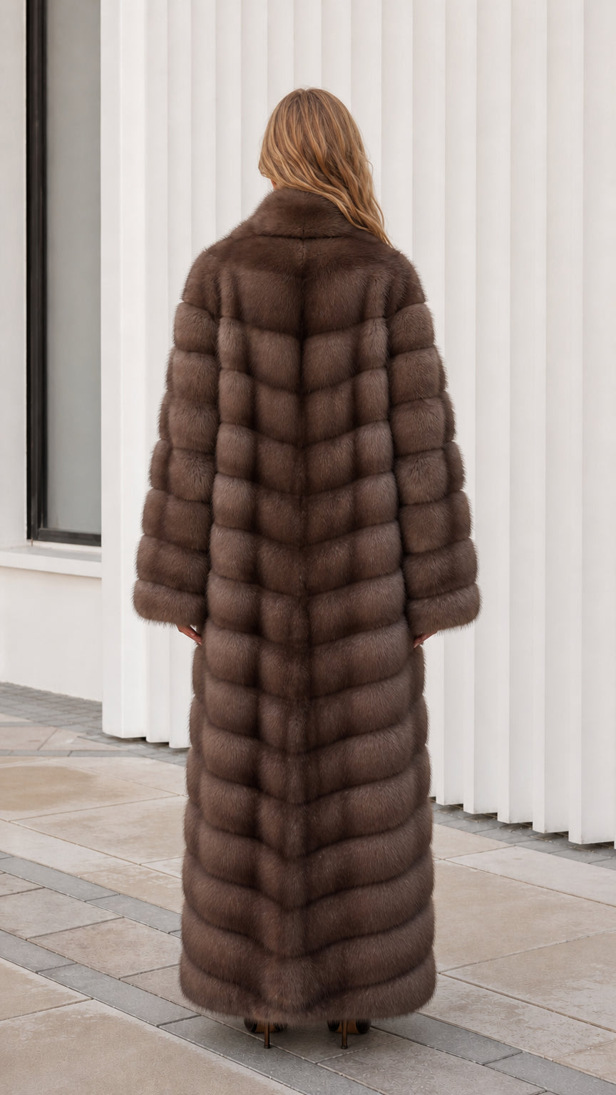 Back view of model showing full-length paneled texture of mocha brown faux fur coat