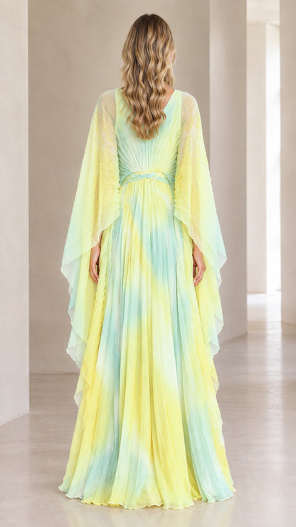 Back view of yellow ombre pleated evening gown showing V-back and cape drape