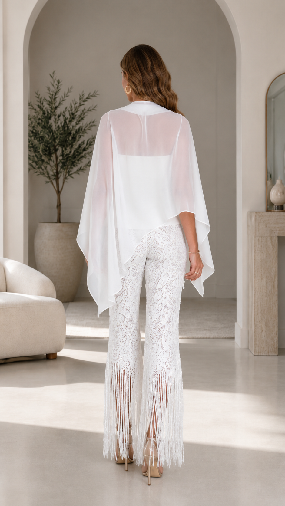 Back view of white cape top and textured flare pants with fringe