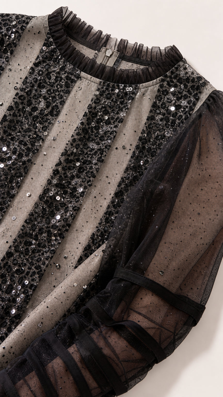 Close-up detail of the ruffled crew neckline and vertical sequin stripes on sheer mesh