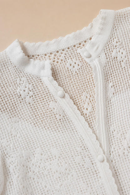 Close-up detail of white crochet lace knit texture and button closure