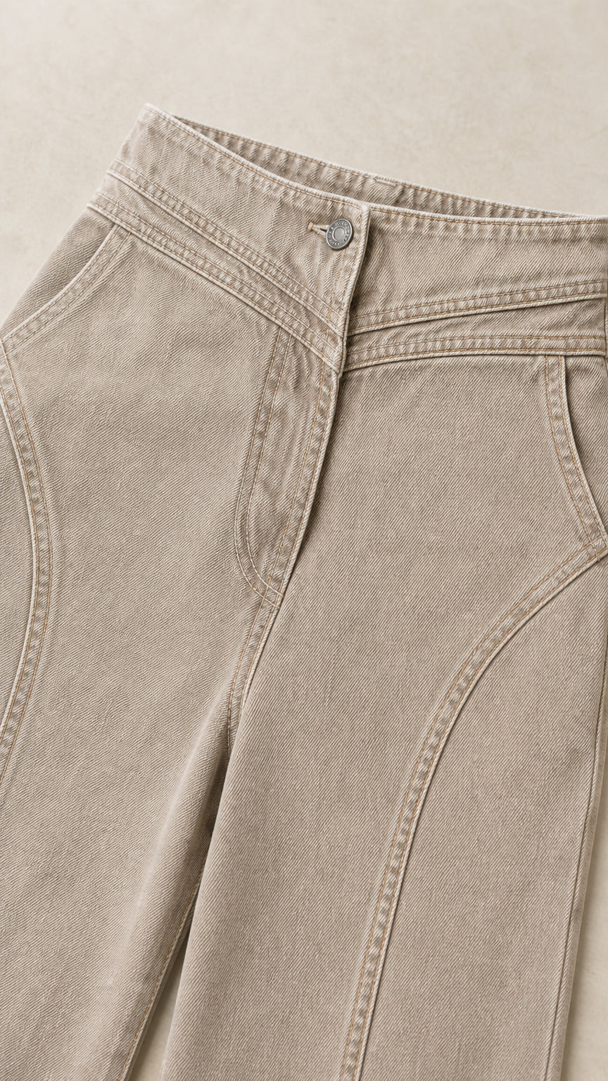 Close-up detail of high waistband, button closure, and curved yoke seams