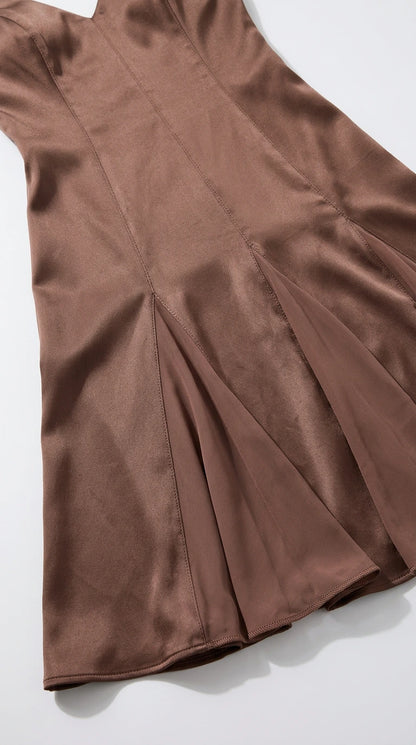 Close-up detail of panel stitching and flared skirt of brown satin maxi dress