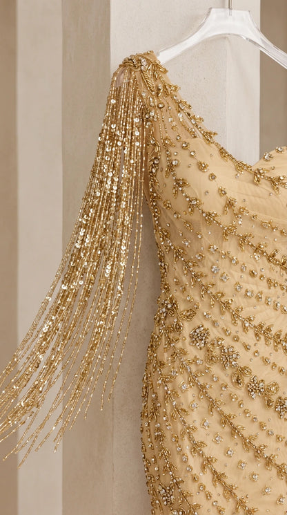 Close-up detail of shimmering sequin beadwork and beaded tassel fringe sleeve on gold dress