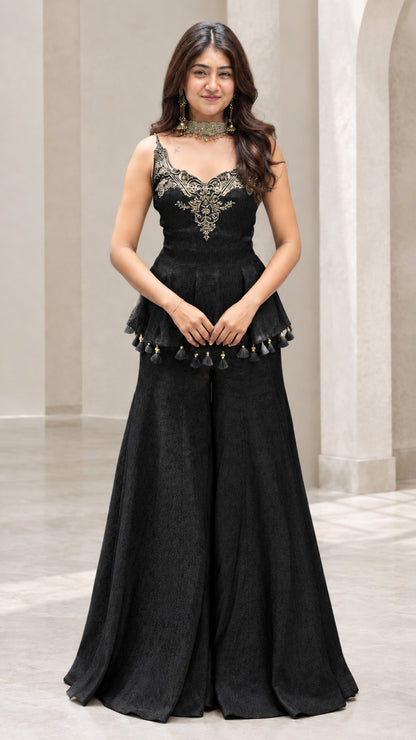 Front view of woman wearing black embroidered peplum sharara pants set
