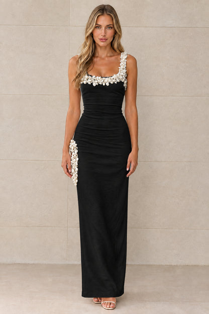 Front view of black sleeveless column maxi dress with white 3D floral trim