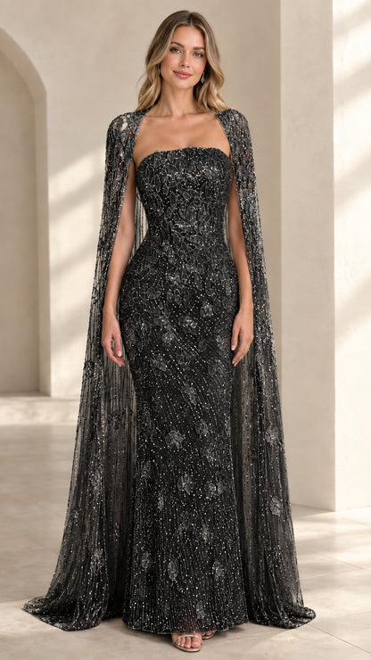 Front view of black beaded strapless formal gown with sheer matching cape