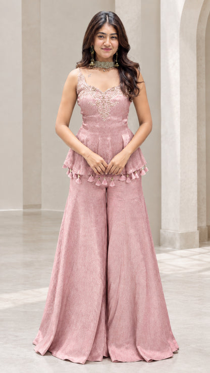 Front view of woman wearing dusty pink embroidered peplum sharara pants set