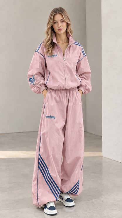 Front view of woman wearing pink two-piece tracksuit set with blue stripes