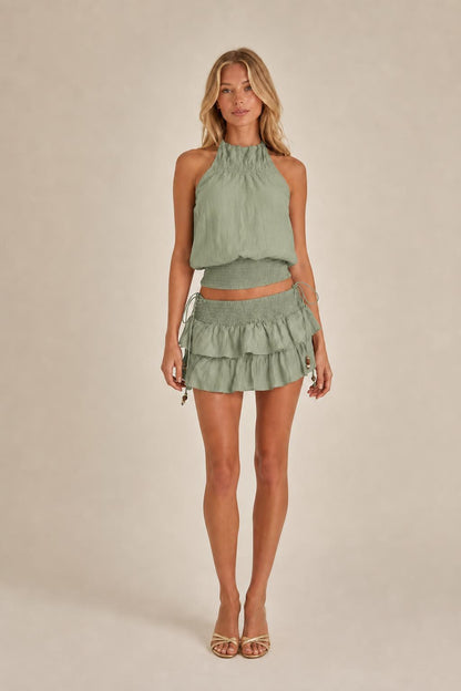 Model wearing sage green halter top and ruffled mini skirt set