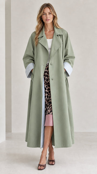 Front view of woman wearing sage green long trench coat with striped cuff accents