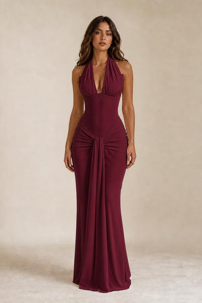 Front view of woman wearing burgundy draped halter neck maxi dress
