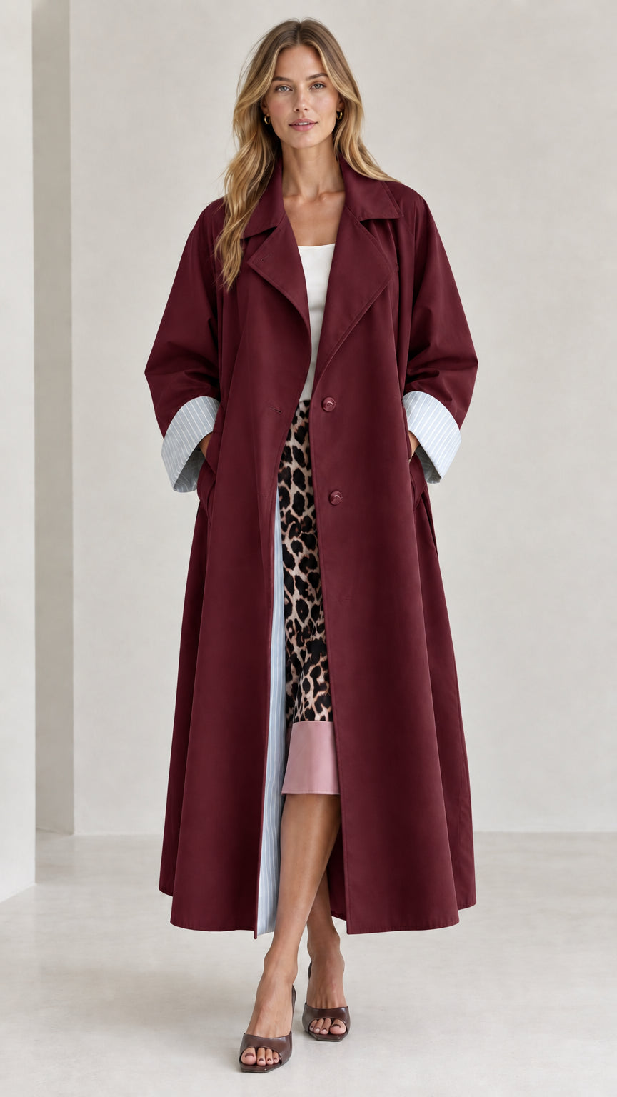 Front view of woman wearing burgundy wine long trench coat with striped cuff accents