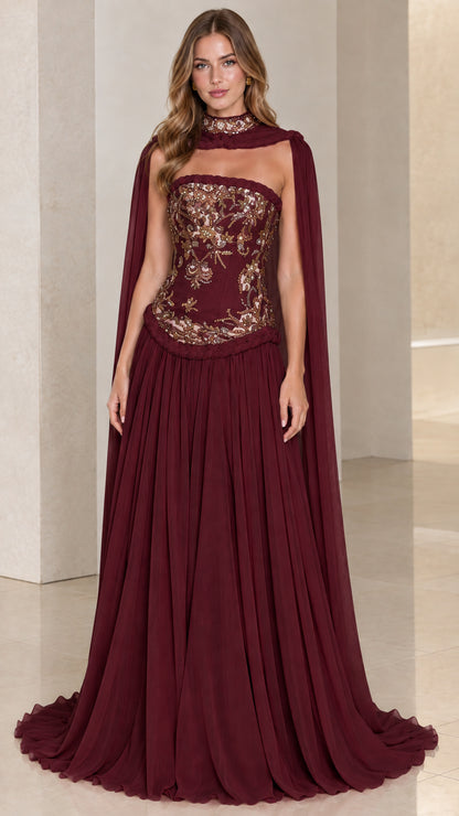 Burgundy strapless evening dress with gold embellishment and flowing sheer cape
