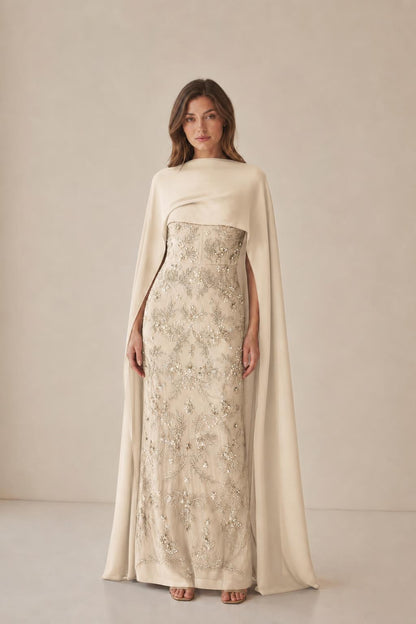 Model wearing champagne beaded dress with cape overlay