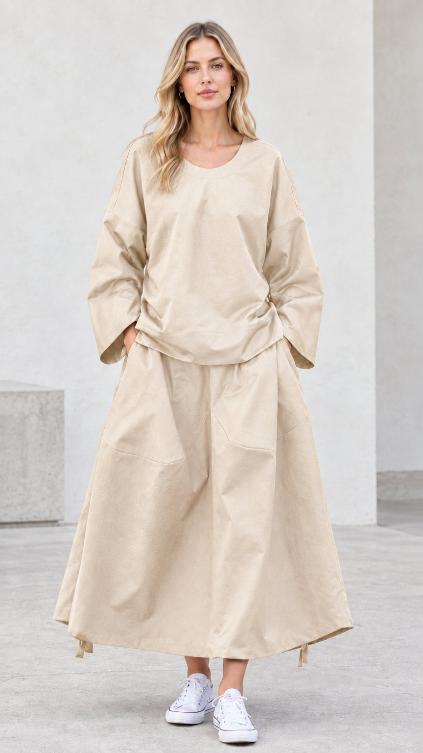 Front view of model wearing beige neutral long sleeve top and maxi skirt set
