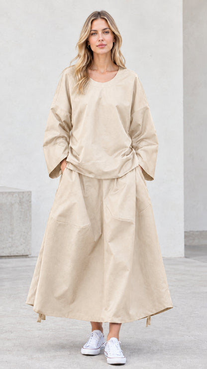 Front view of model wearing beige neutral long sleeve top and maxi skirt set