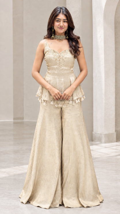 Front view of woman wearing champagne gold embroidered peplum sharara pants set